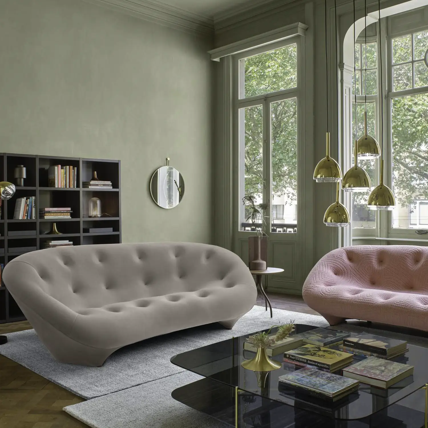 Beige and Pink couches in a living room with sage green walls and grey carpets, bookshelf and coffee table