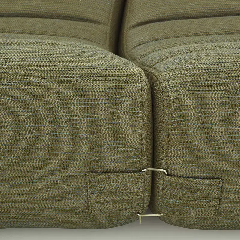Close-up of two green fabric couch cushions connected by a metal clip at the base.