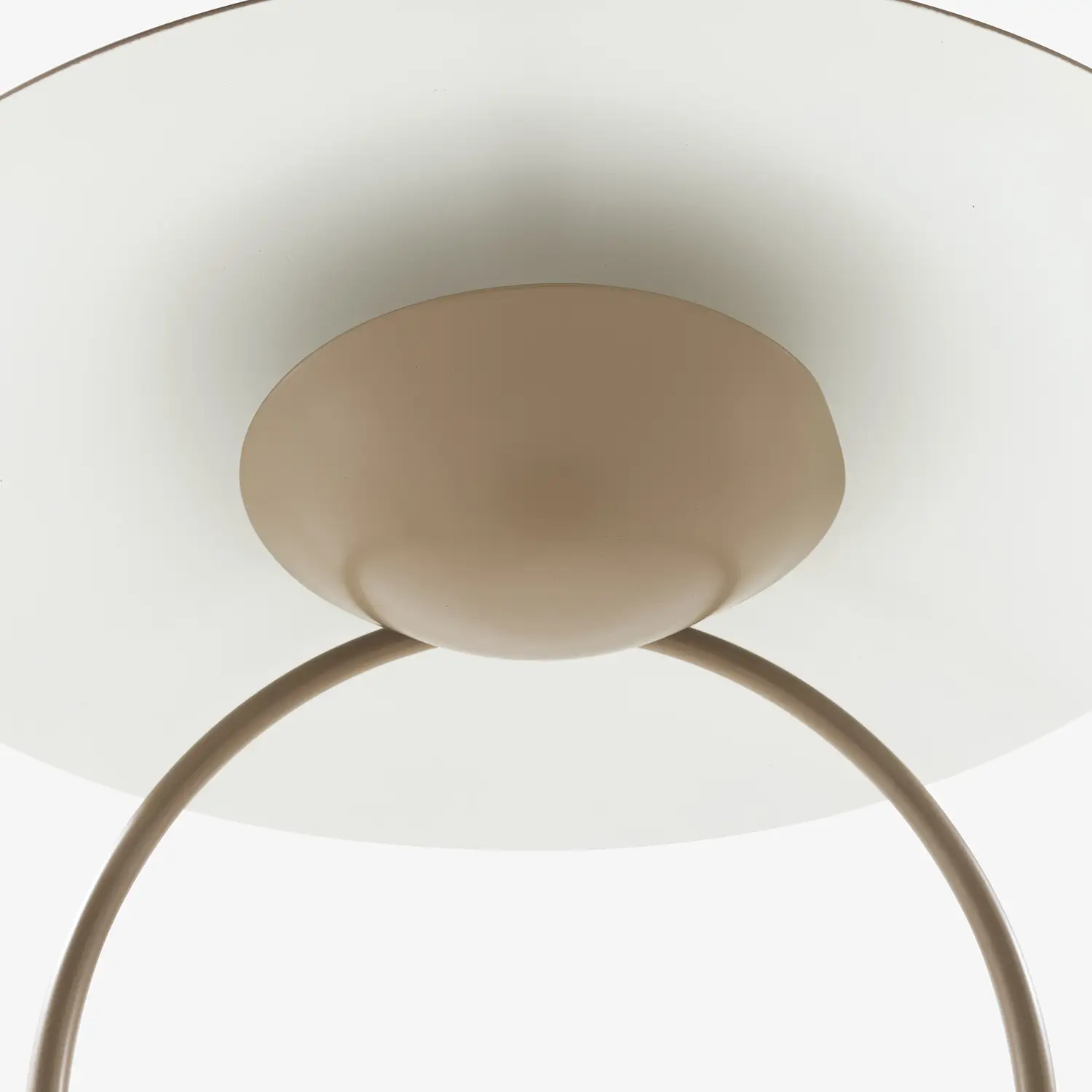 Close-up from below of a taupe-colored modern table lamp with an arched stand and a round base.