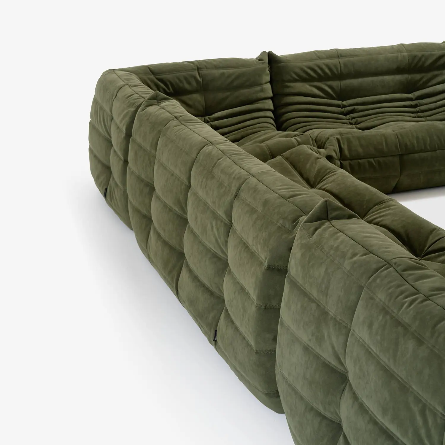 Close-up of an olive green, tufted sectional sofa with soft fabric upholstery.