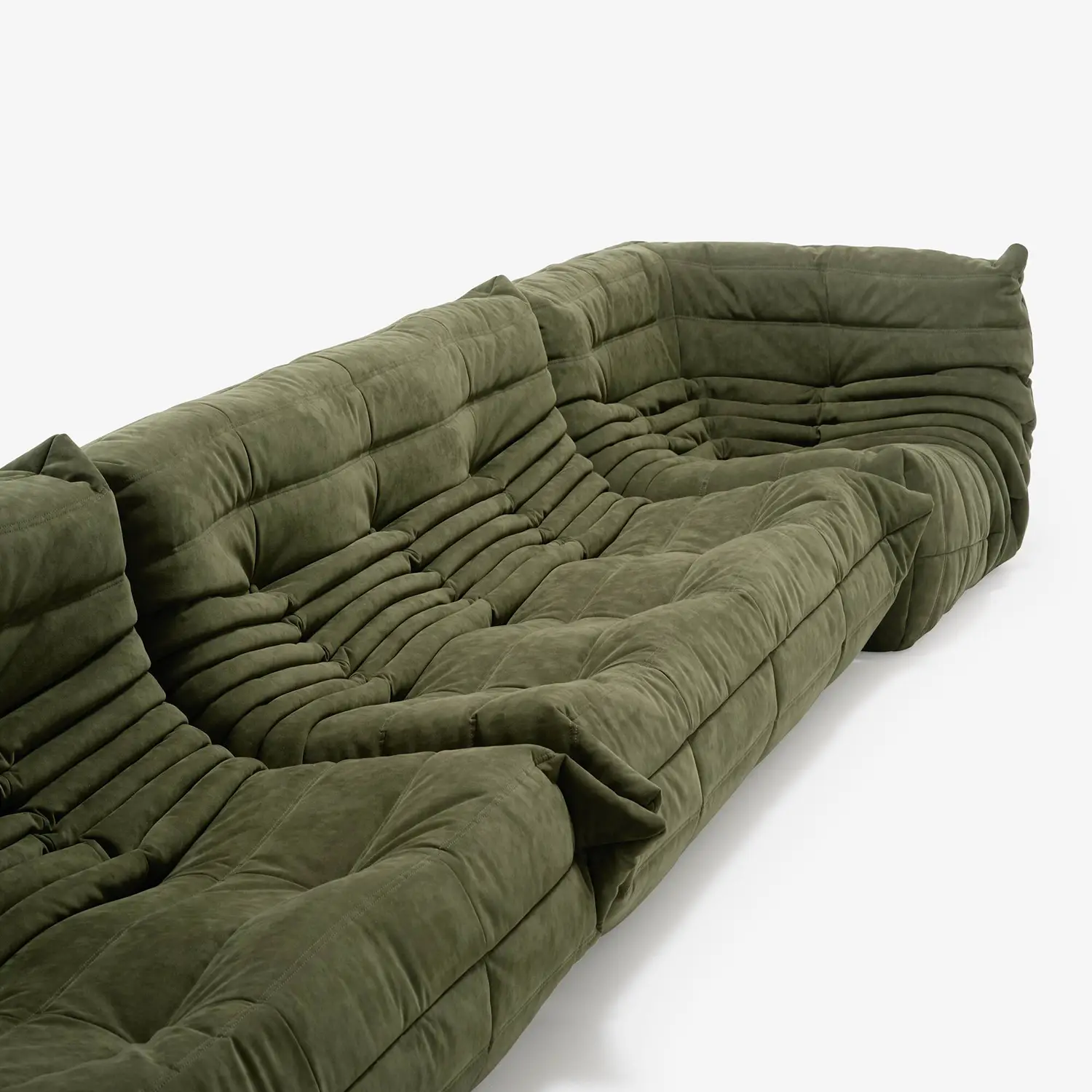 Olive green modular sectional sofa with plush, tufted cushions and a soft suede-like fabric.